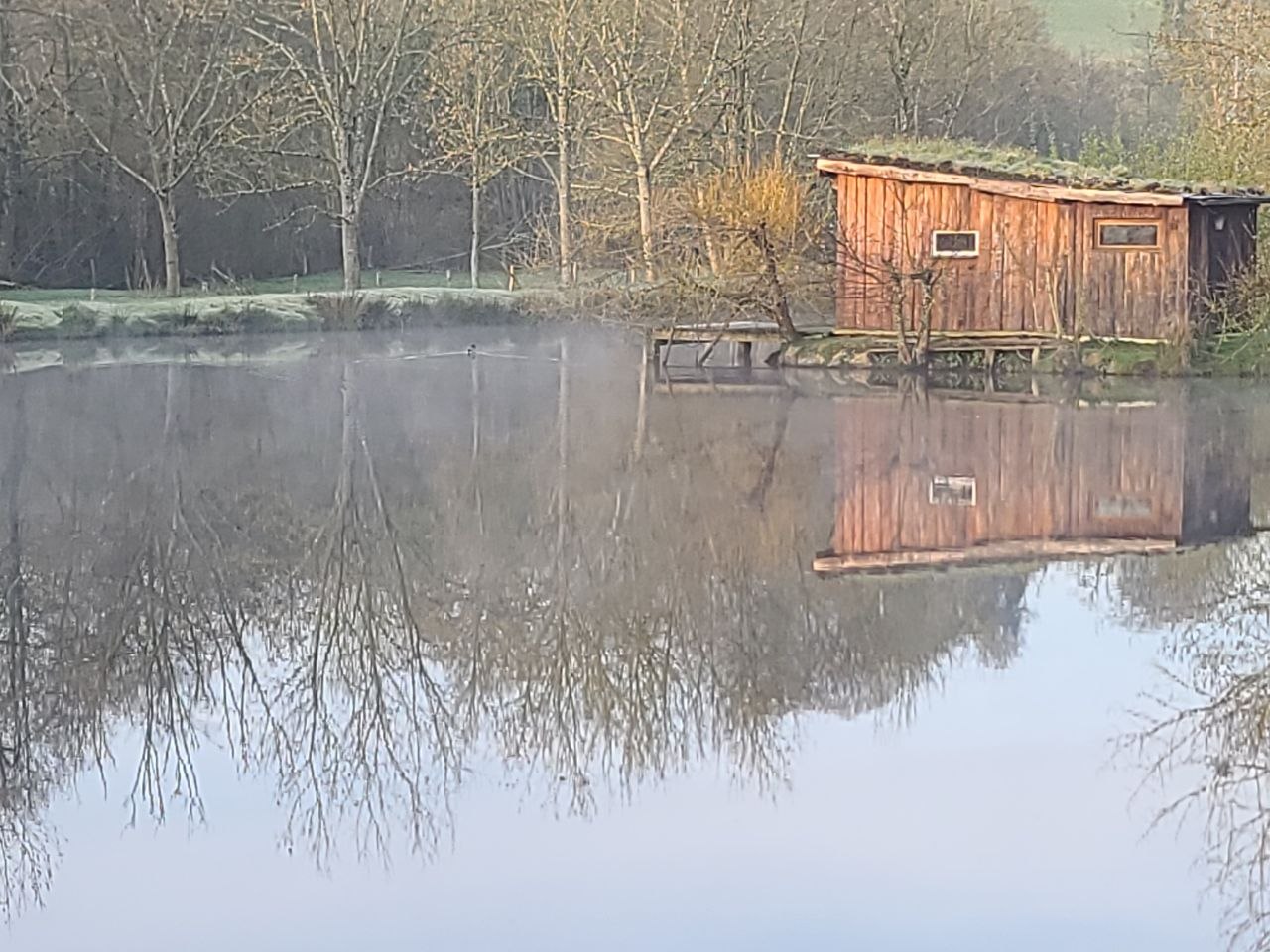 La cabane au toit végétalisé reflétée dans l'étang
